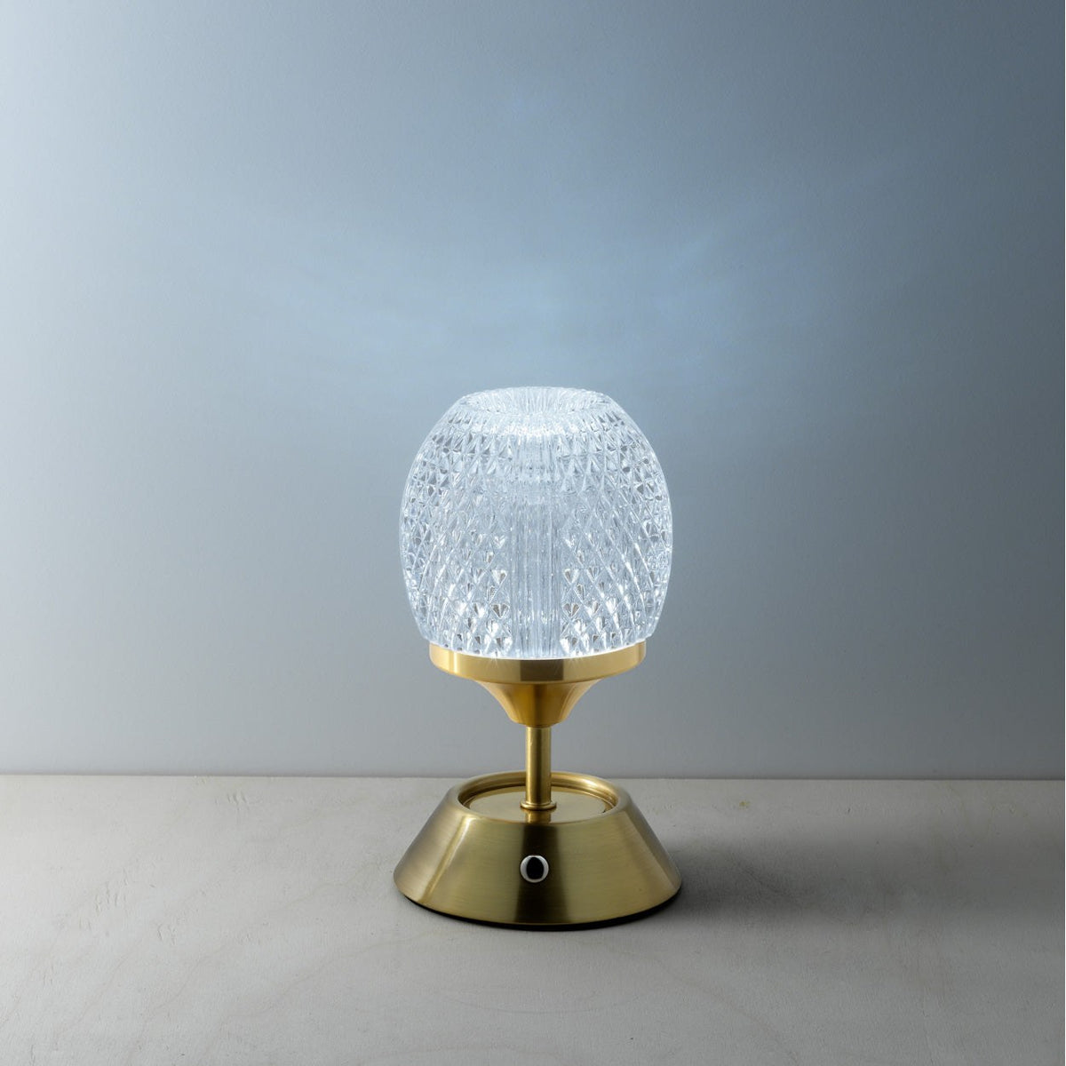 Lampe Glow Sinatra allumée en lumière froide devant un mur bleuté