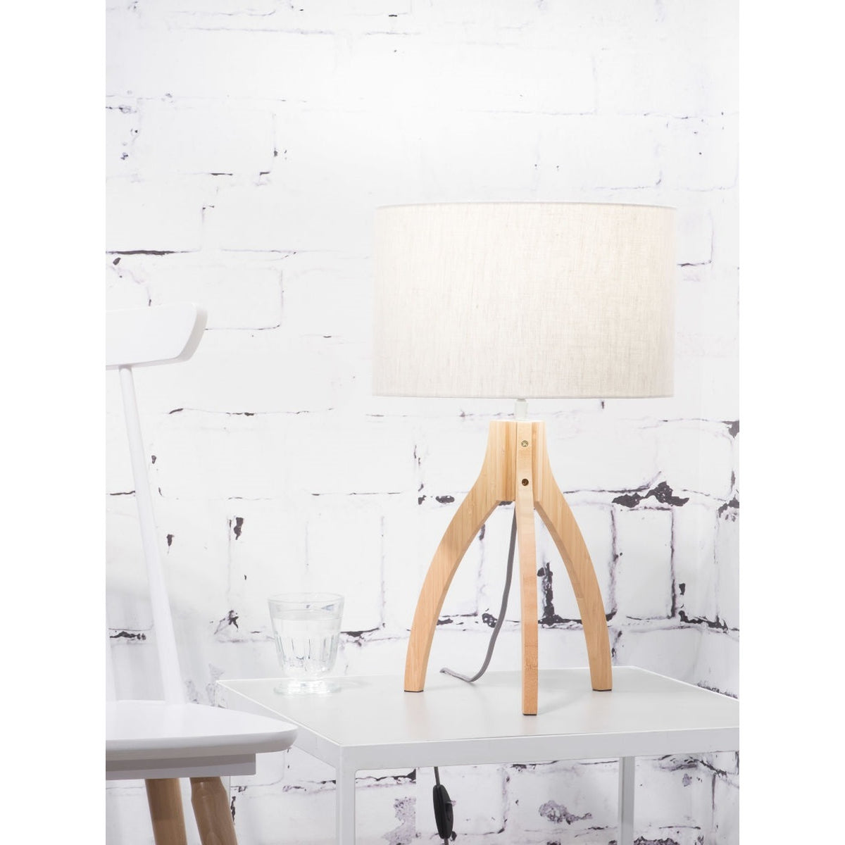 Lampe Annapurna lin naturel clair sur une table d'appoint avec un verre et l'interrupteur sur le câble