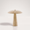 Lampe de table champignon Consett éteinte sur fond clair, pied conique et chapeau bombé en travertin aux pores apparents