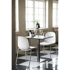 Lampe Bradford noire sur une table carrée noire entourée de deux chaises blanches