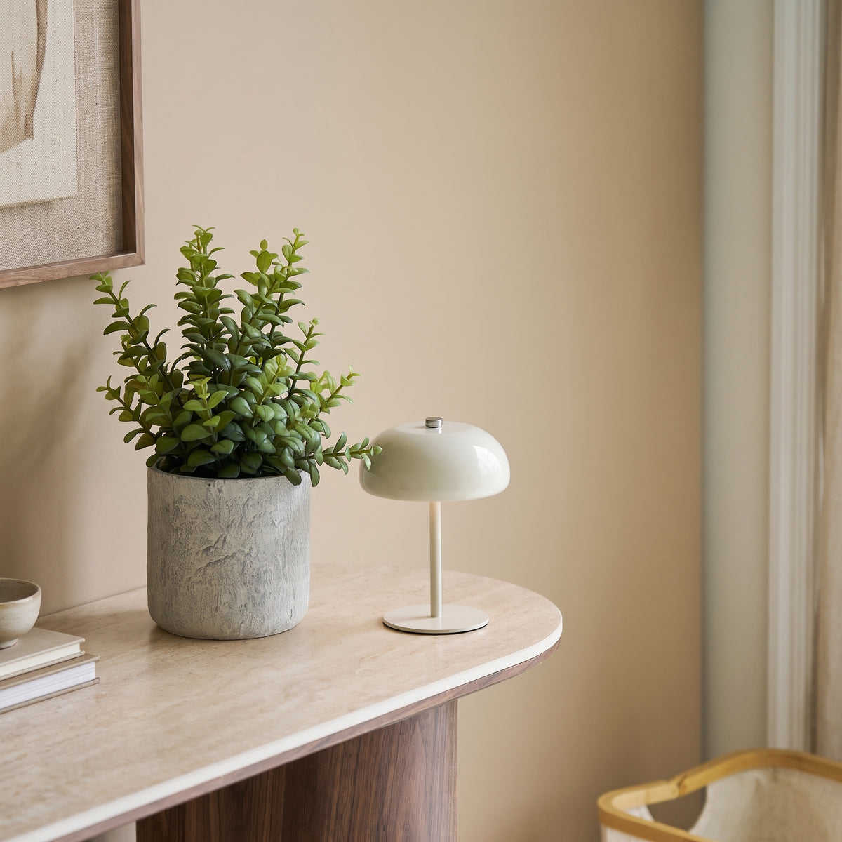 Lampe Margate Laque grège sur le bord d'une console au plateau clair, à côté d'une plante