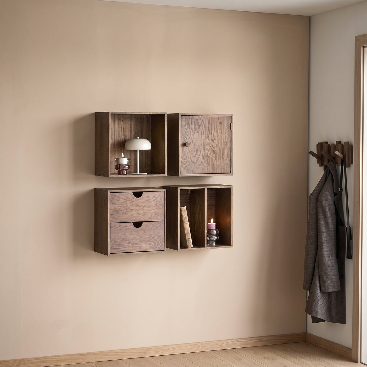 Lampe Margate Laque grège posée dans un cube mural en bois foncé, près de bougies et de patères