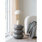Lampe Sheffield posée sur une table d'appoint grise brillante près d'une fenêtre et d'un fauteuil bouclette