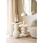 Lampe Sheffield sur une table d'appoint sculpturale blanche près d'un miroir rond et de deux bougeoirs blancs