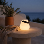 Lampe lanterne Derry blanc givré anse cuir allumée sur table en pierre face à la mer au crépuscule