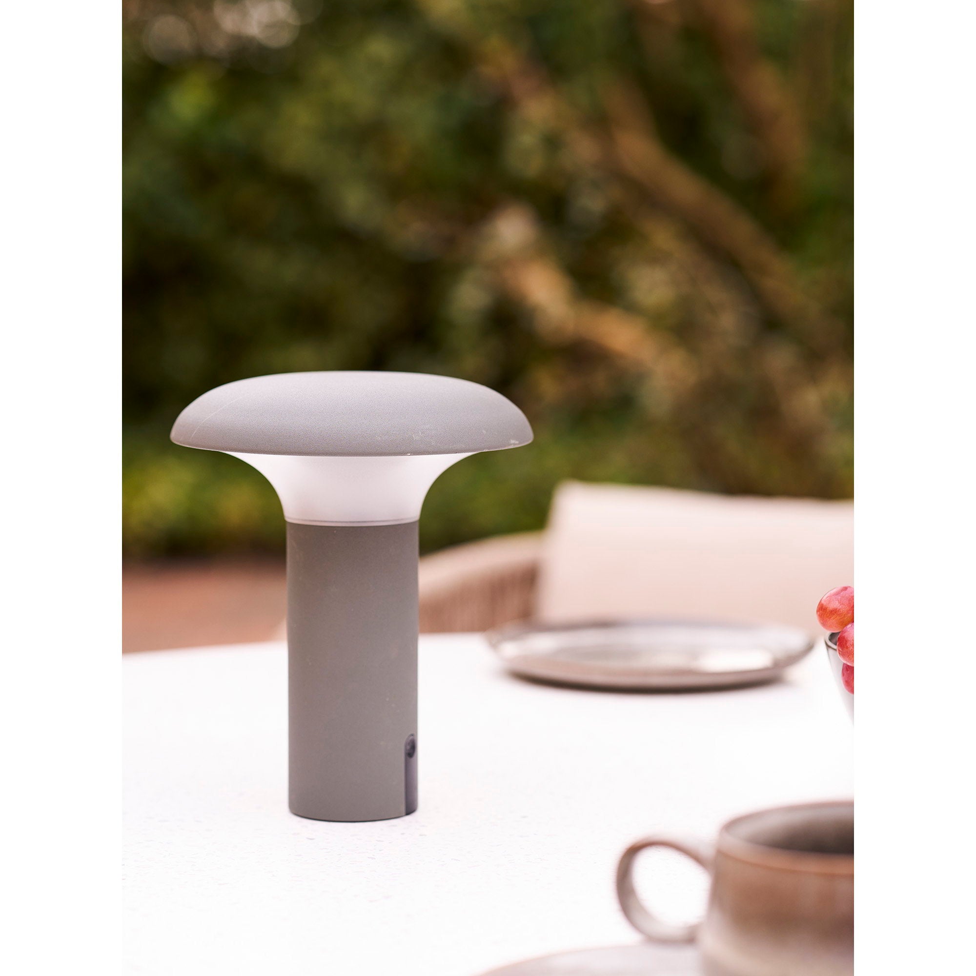 Lampe Ramsey gris mat posée sur table jardin blanc ambiance déjeuner extérieur