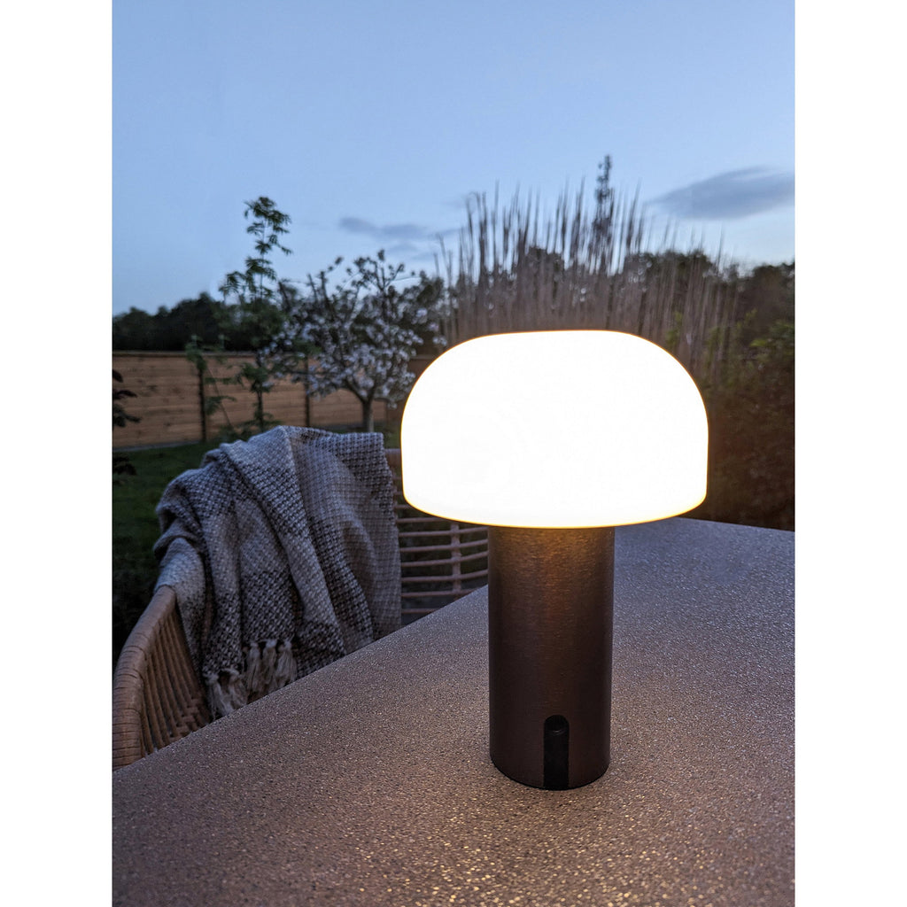 Lampe Soham cuivre brossé allumée terrasse nuit ambiance chaleureuse table extérieure