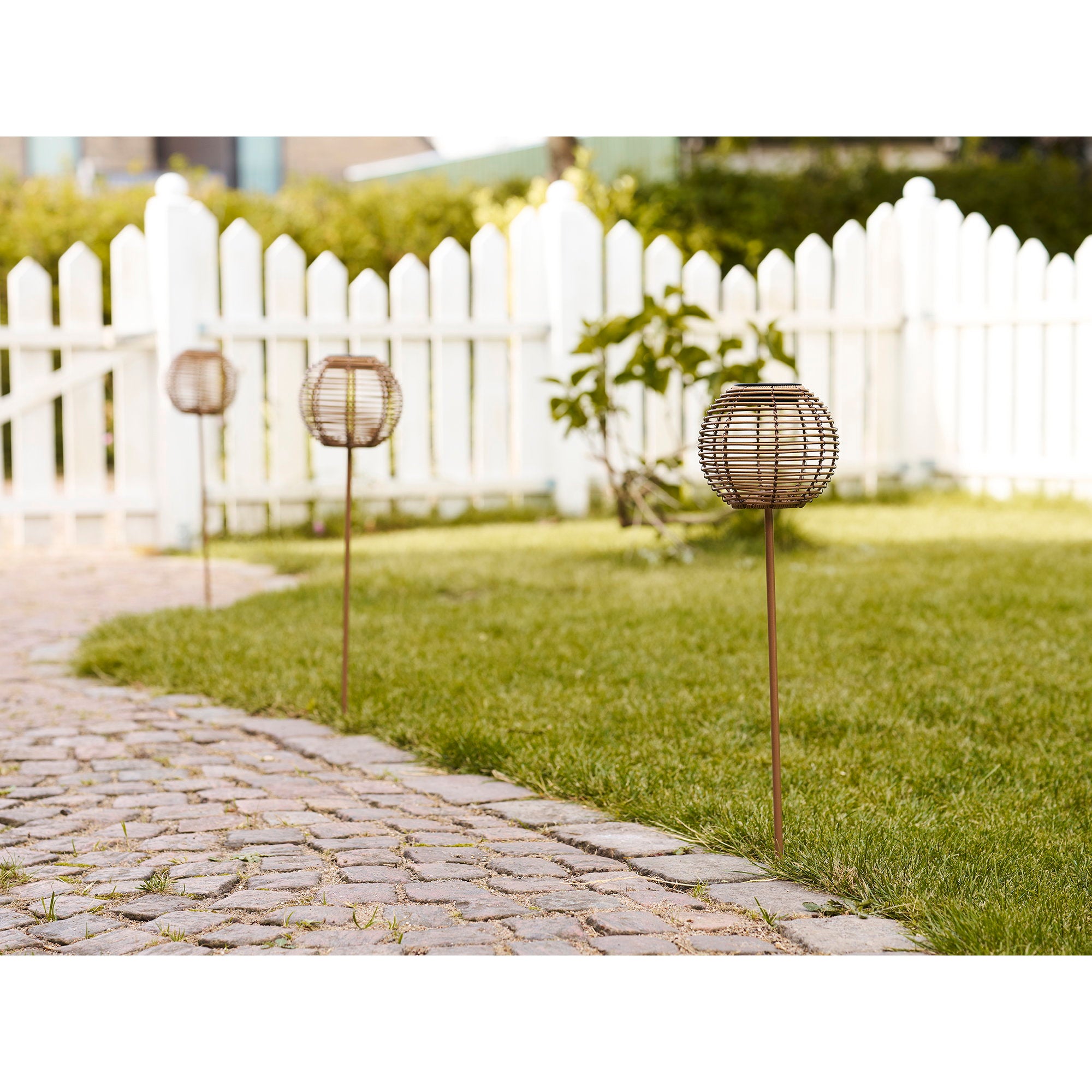 Lampes solaires Carlisle sur piquet alignées allée jardin gazon clôture blanche