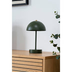 Lampe Holt vert kaki et laiton posée sur une commode en bois clair dans un salon naturel