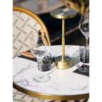 Lampe de table nomade Lyneham laiton allumée table restaurant bois ambiance bistrot