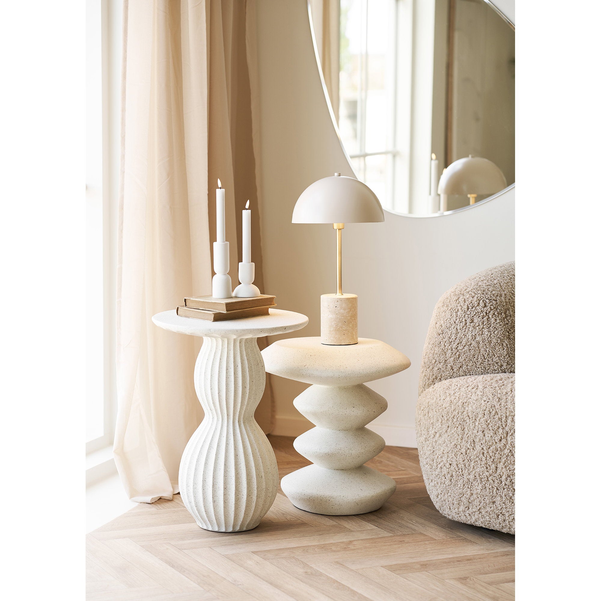 Lampe Sheffield beige sur table basse salon décoré, miroir rond et fauteuil bouclette