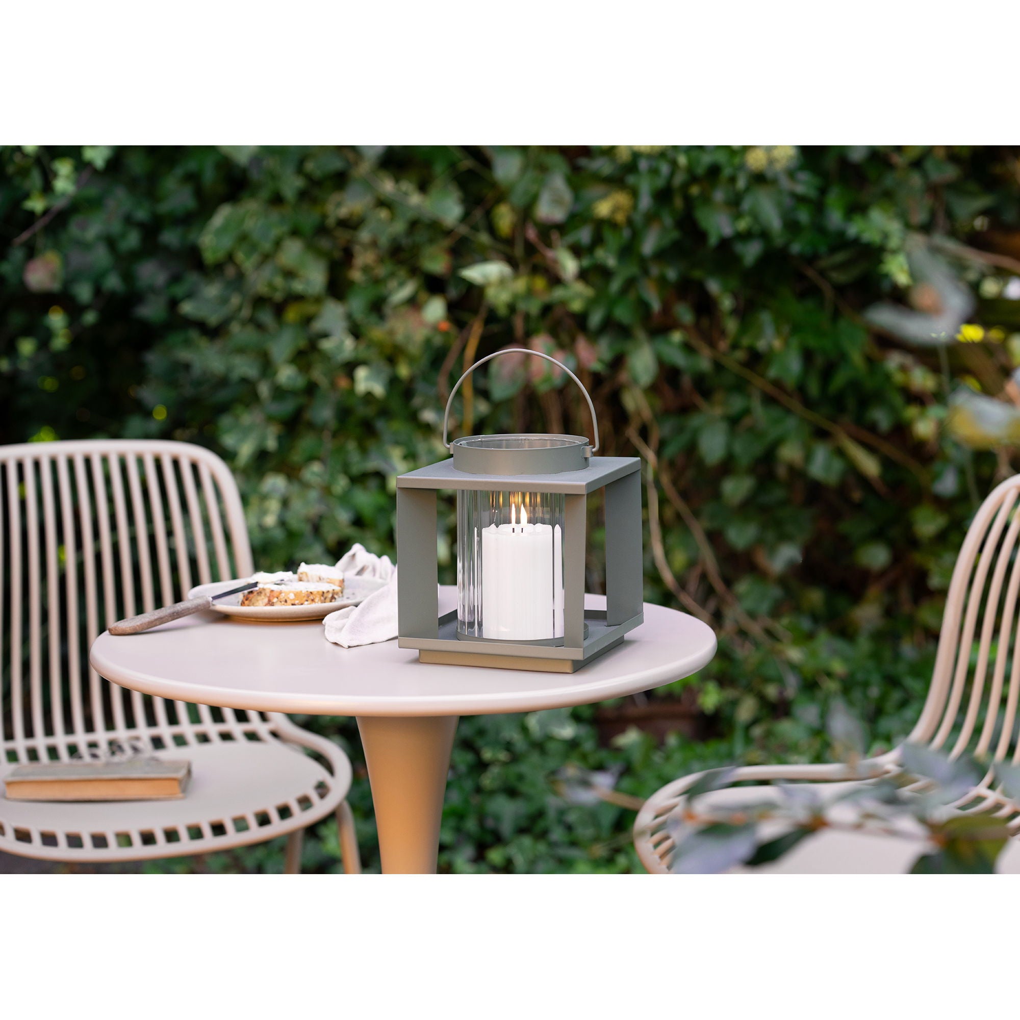 Lanterne photophore Lohals vert kaki sur table de jardin ronde, ambiance repas extérieur