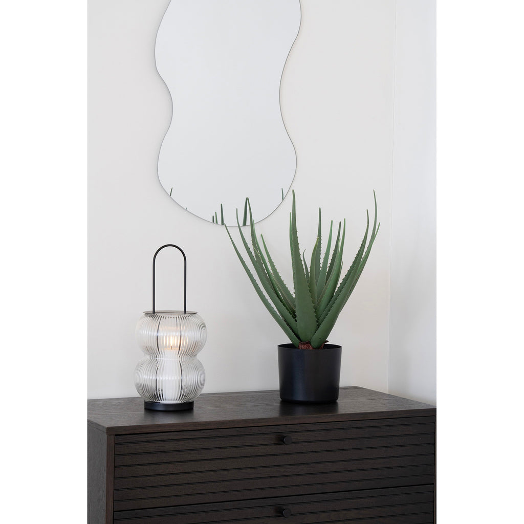 Lanterne Lucena bougie allumée sur commode bois sombre avec miroir organique mural