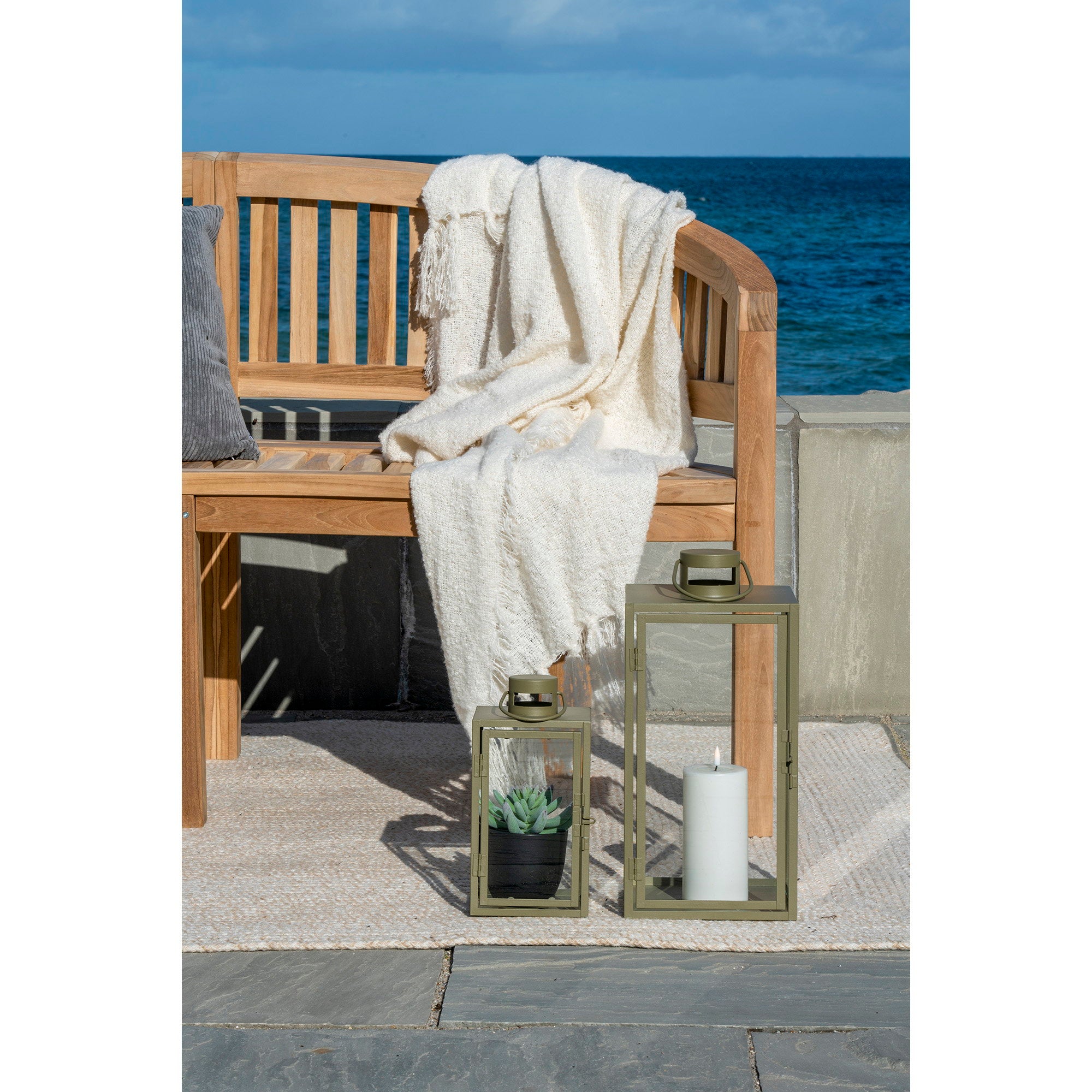 Lot de 2 lanternes Corfu vert kaki posées au sol terrasse bord de mer avec banc en bois