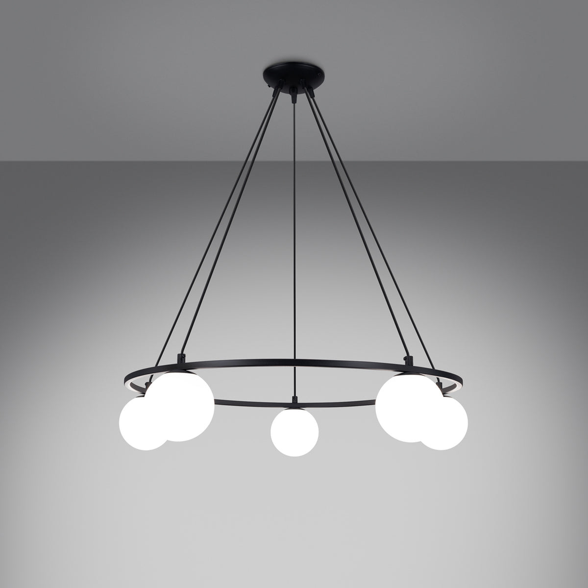 Lustre Yoli 5 allumé sur fond gris les cinq boules de verre opale diffusent une lumière douce