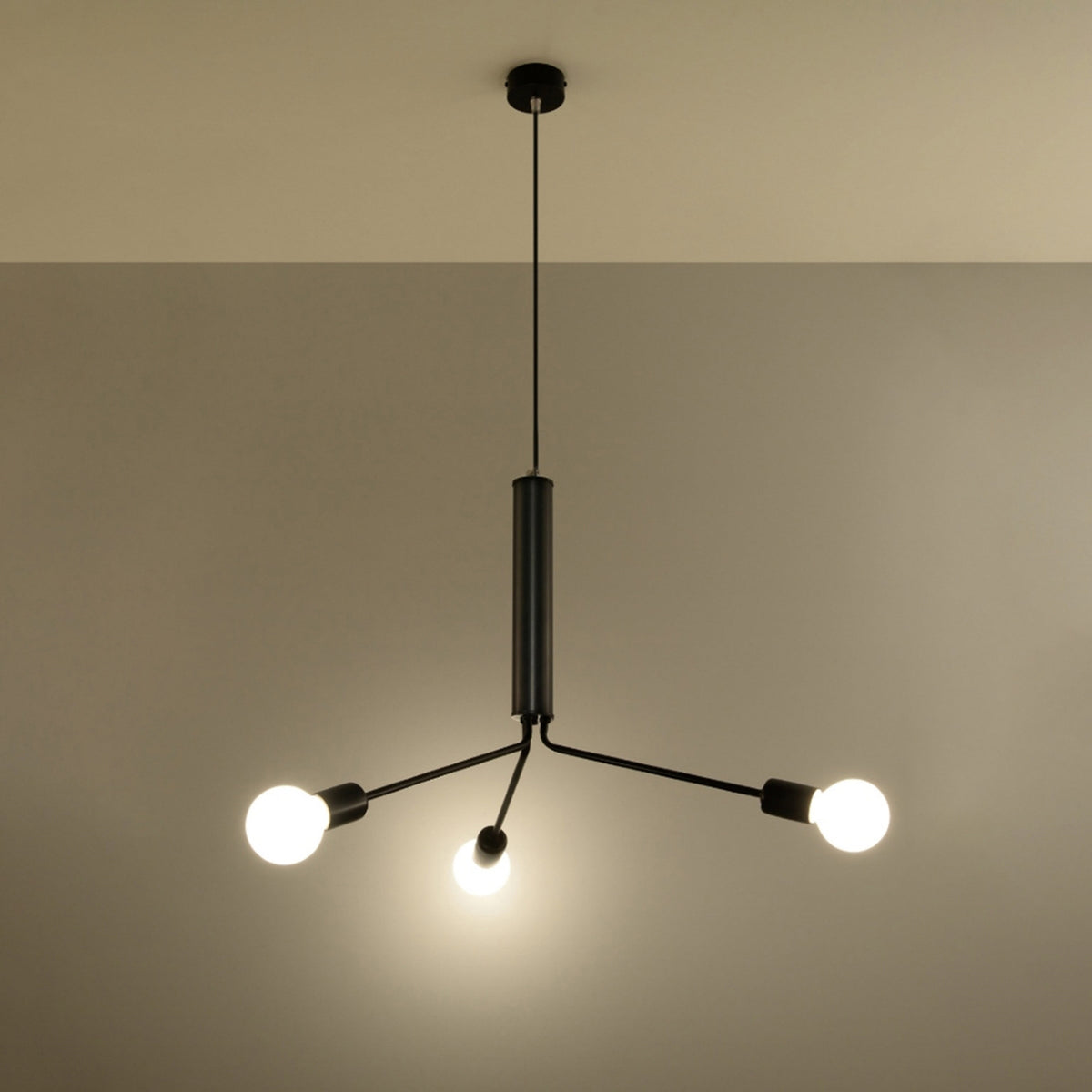 Lustre Duomo noir allumé avec ses trois ampoules globe éclairant un mur beige