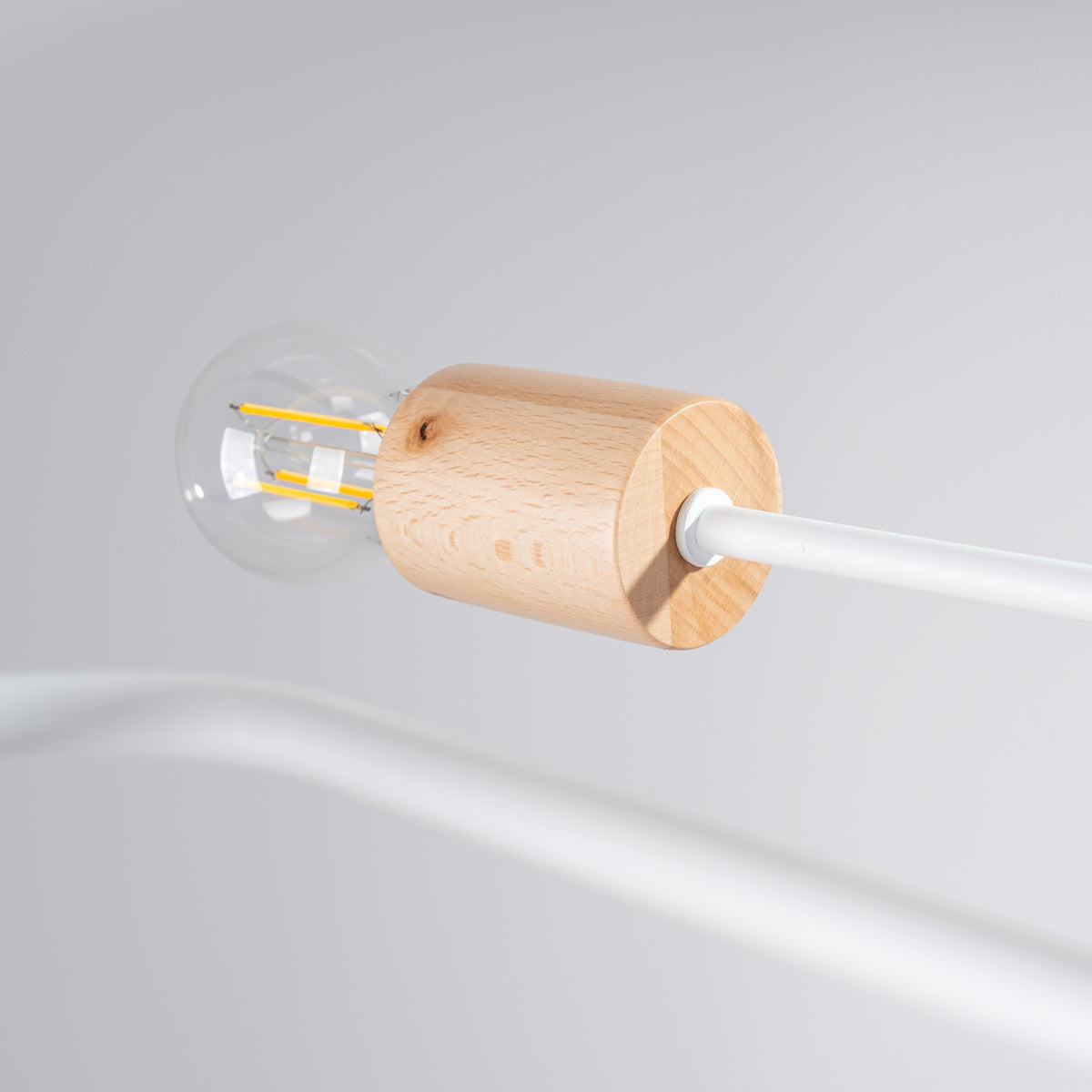 Douille en bois et ampoule à filament éteinte sur un bras métal blanc du lustre Timbo