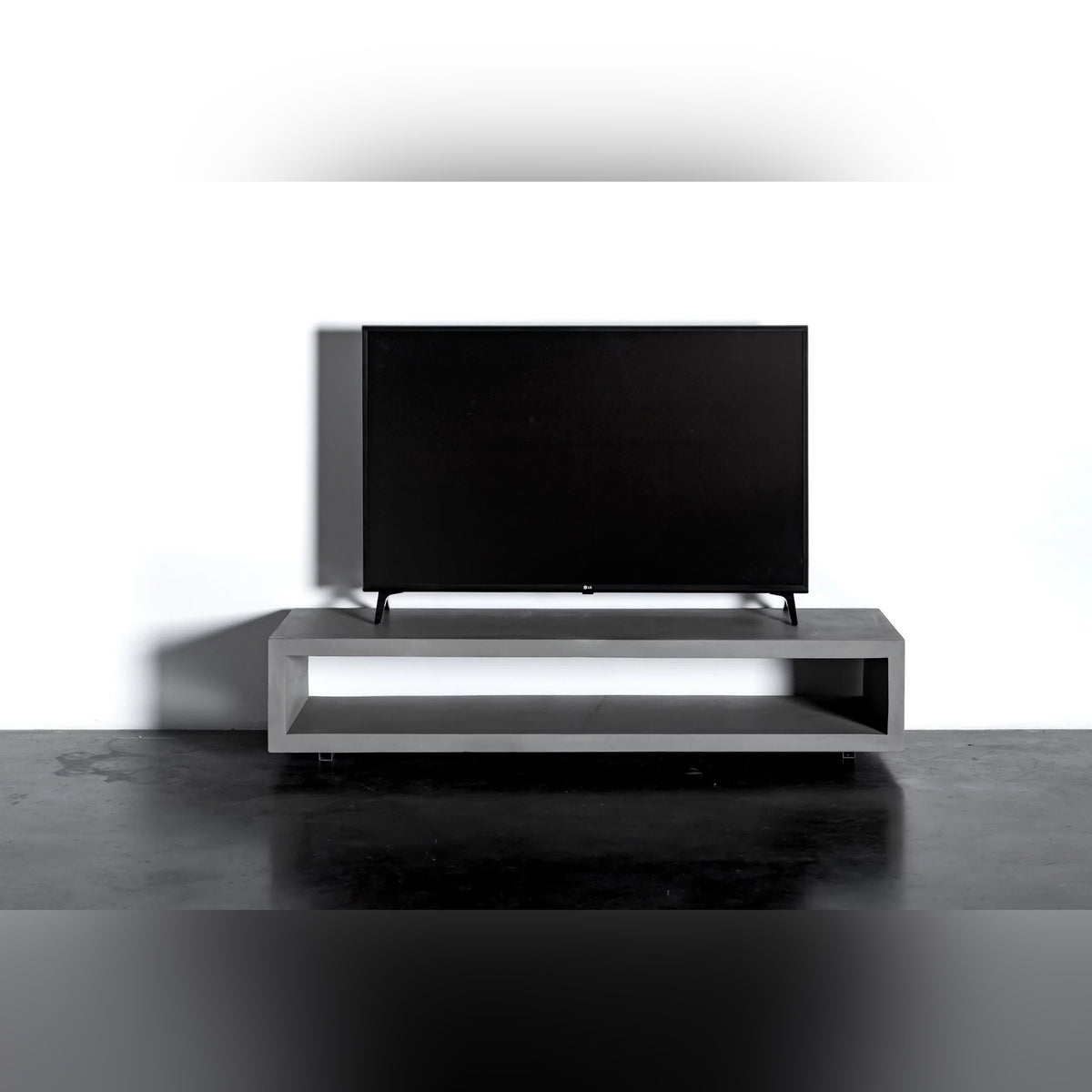 Meuble TV Monobloc en béton vu de face avec son téléviseur et sa niche traversante