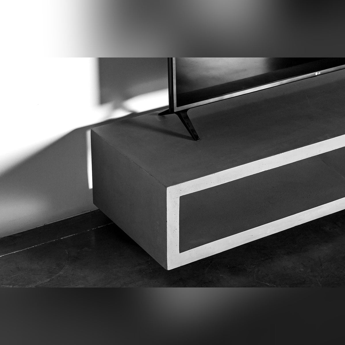 Détail du plateau du meuble TV Monobloc sous le pied d'un téléviseur