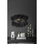 Miroir Black Eye sur un mur sombre au-dessus d'une console avec des boîtes blanches et des sculptures