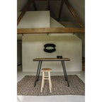 Miroir Black Eye sur un mur blanc sous une charpente en bois au-dessus d'une table haute