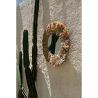 Miroir Palm Tree en raphia vu de biais sur un mur crépi où se reflète un cactus