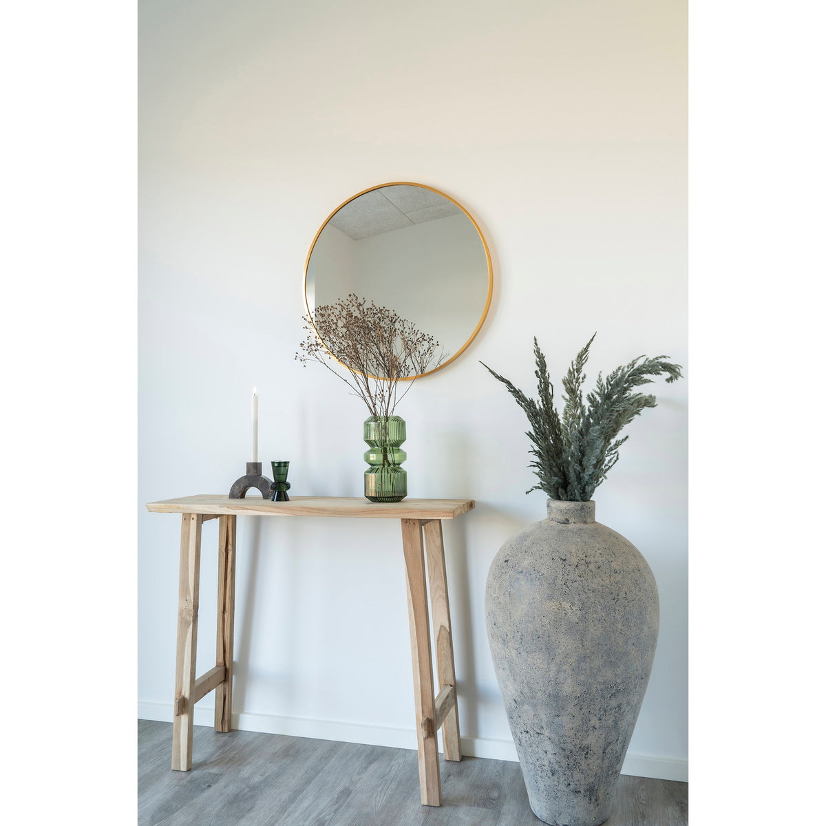 Miroir rond Madrid aluminium doré au-dessus d'une console en bois brut près d'une grande jarre