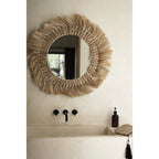 Miroir rond Pretty Blonde en herbe accroché au-dessus d'un lavabo beige à robinetterie noire