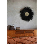 Miroir Simba en herbe rayung noire sur un mur gris au-dessus d'un buffet en teck avec un panier tressé et une boîte en coquillages