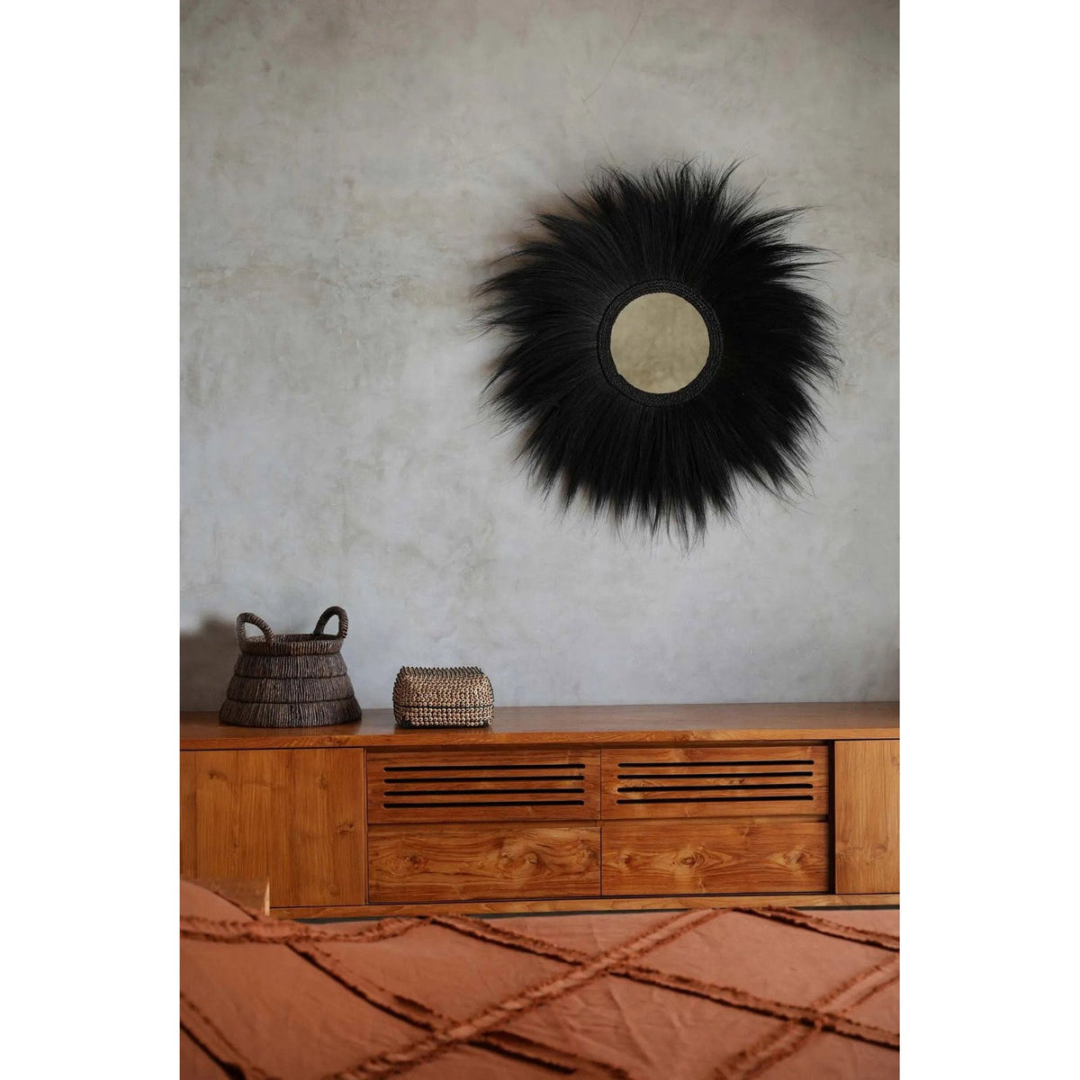 Miroir Simba en herbe rayung noire sur un mur gris au-dessus d'un buffet en teck avec un panier tressé et une boîte en coquillages