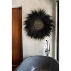 Miroir Simba en herbe rayung noire au-dessus d'une baignoire en pierre à côté d'une porte en lattes de bois