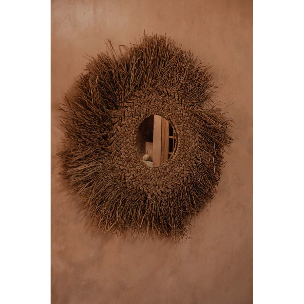 Miroir Early Monday sur un mur enduit terracotta reflétant une porte en bois