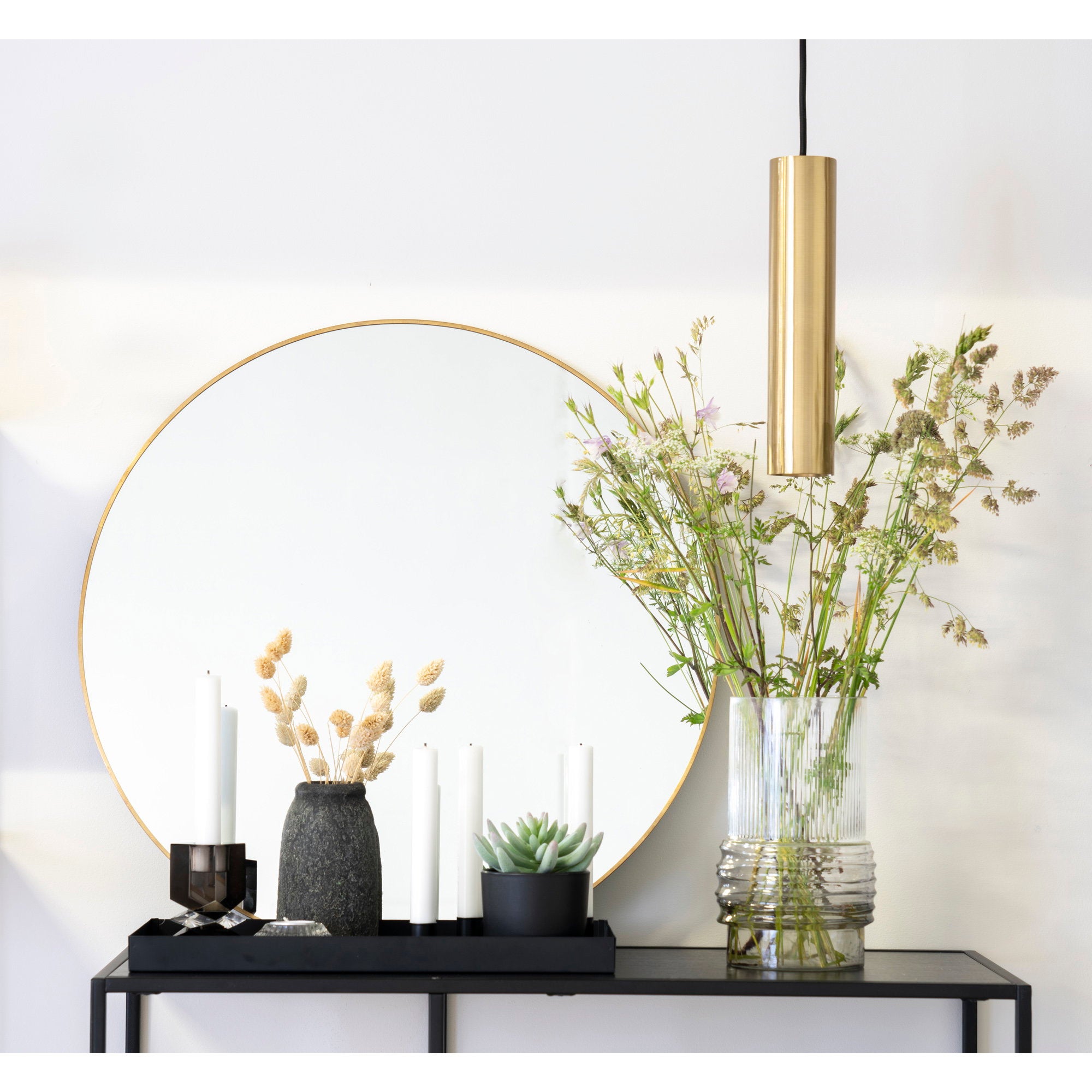 Miroir Jersey rond laiton doré ø60 cm au-dessus d'une console noire avec fleurs