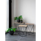 Plante artificielle Monstera dans pot noir au sol près de tables gigognes