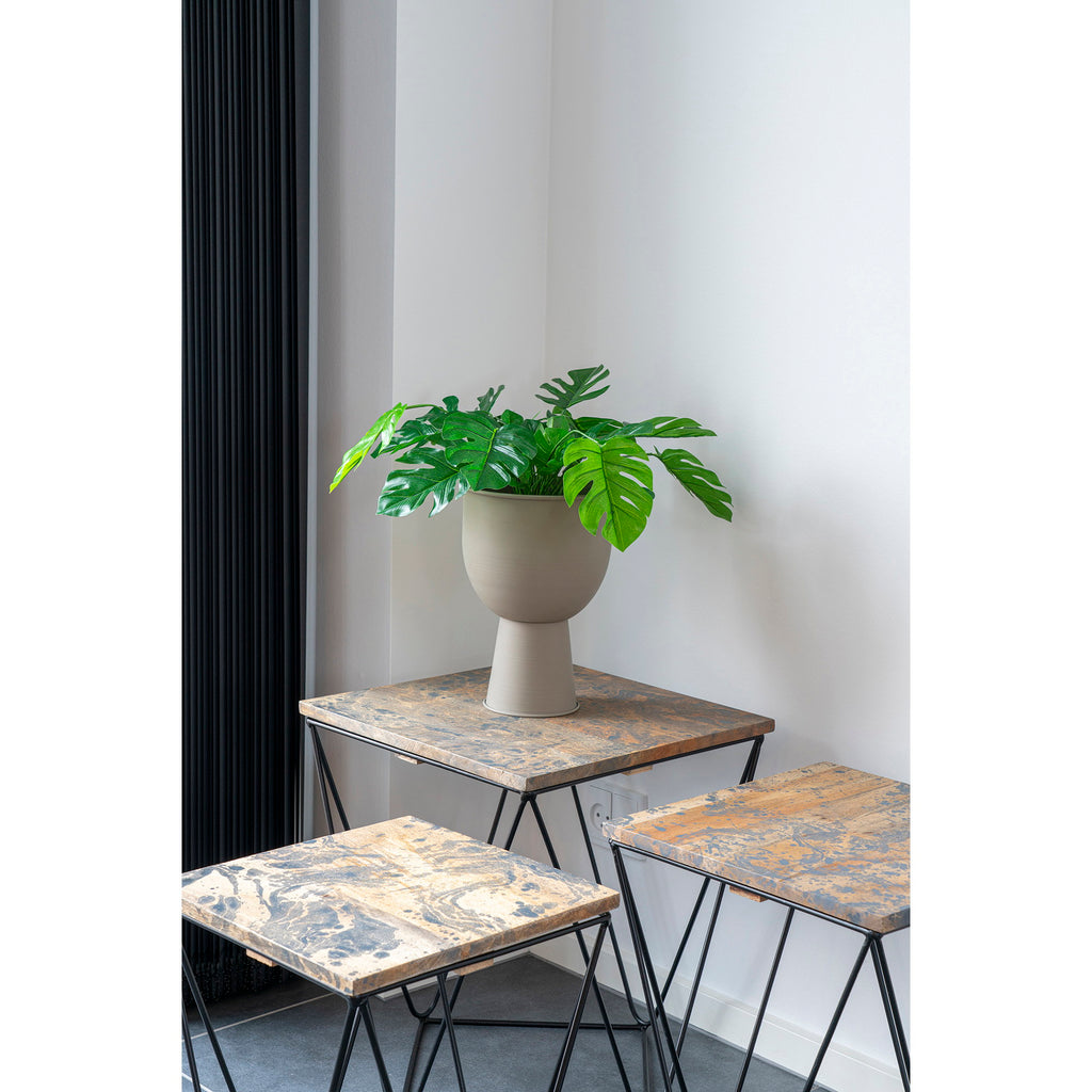 Plante artificielle Monstera dans vase beige posée sur table basse marbre salon moderne