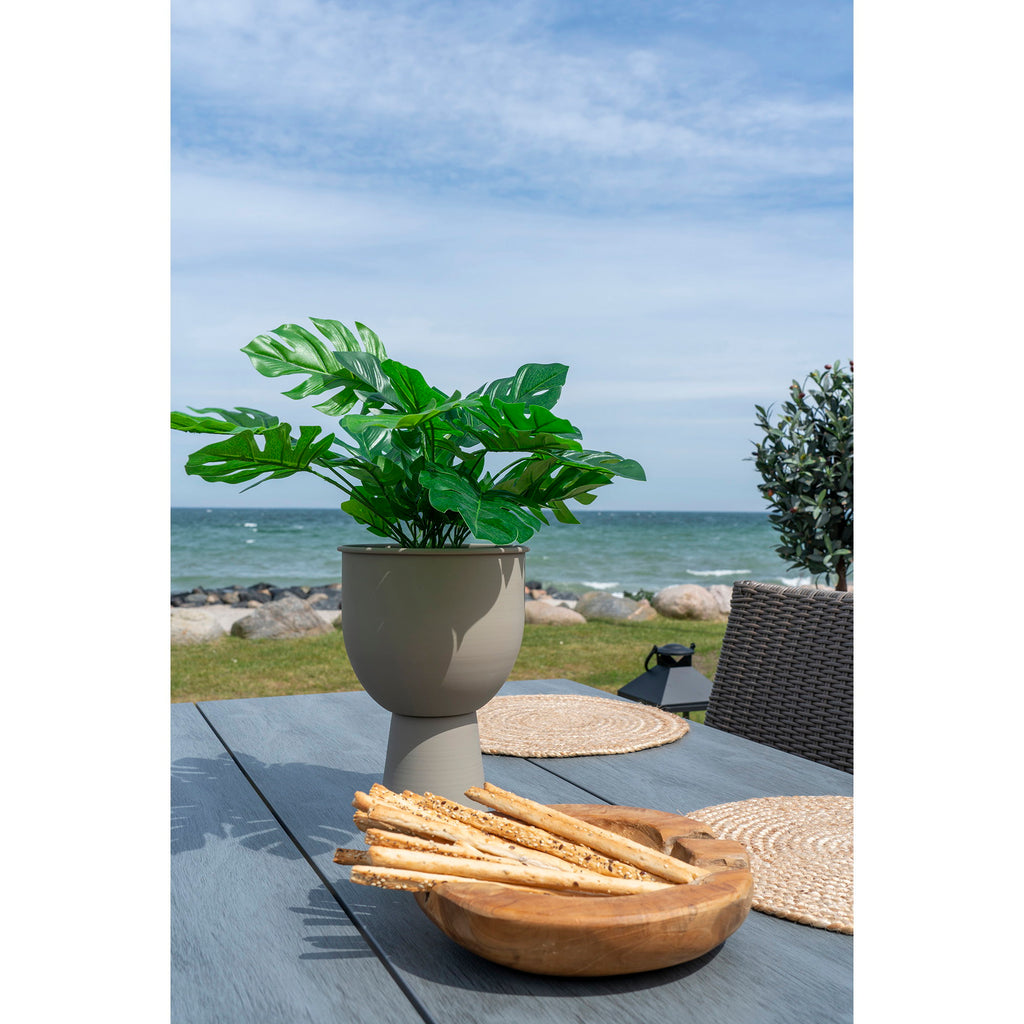 Plante artificielle Monstera dans pot beige posée sur table terrasse bord de mer