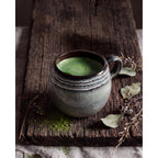 Mug boule Comporta rempli de matcha posé sur une planche en bois brut