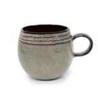 Mug boule Comporta en grès vert de gris vu de profil avec son anse en anneau et son intérieur brun