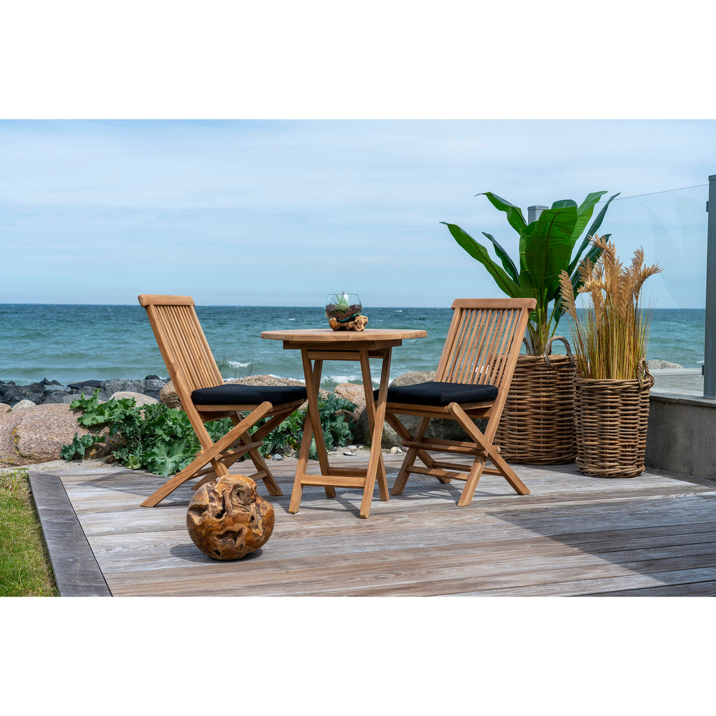 Table pliante teck ronde terrasse bord de mer chaises teck pliantes coussins noirs plantes
