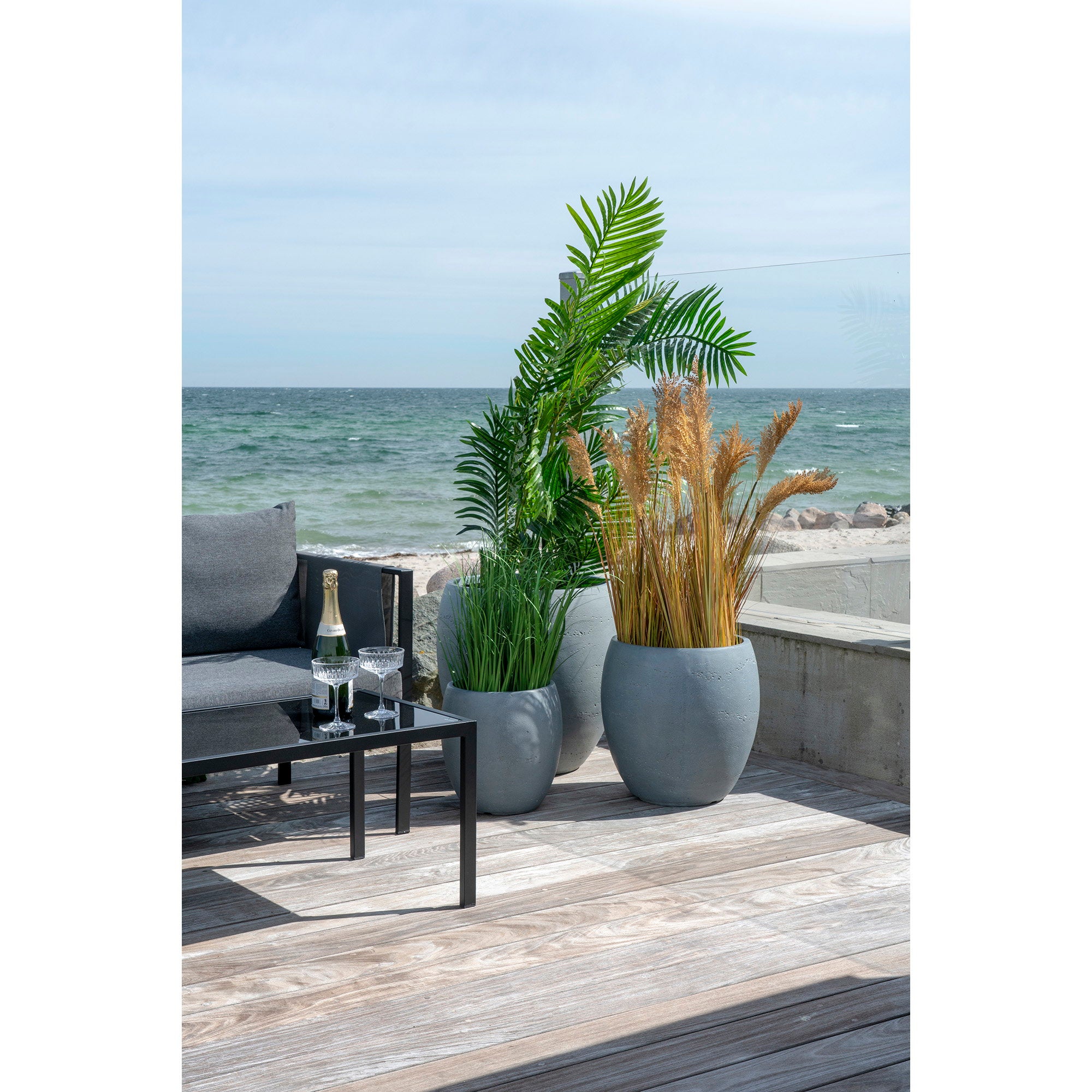 Grand palmier artificiel Areca dans pot béton terrasse bord de mer ambiance estivale
