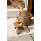Panier Colonial en rotin brun naturel à côté d'un petit tabouret en bois brut