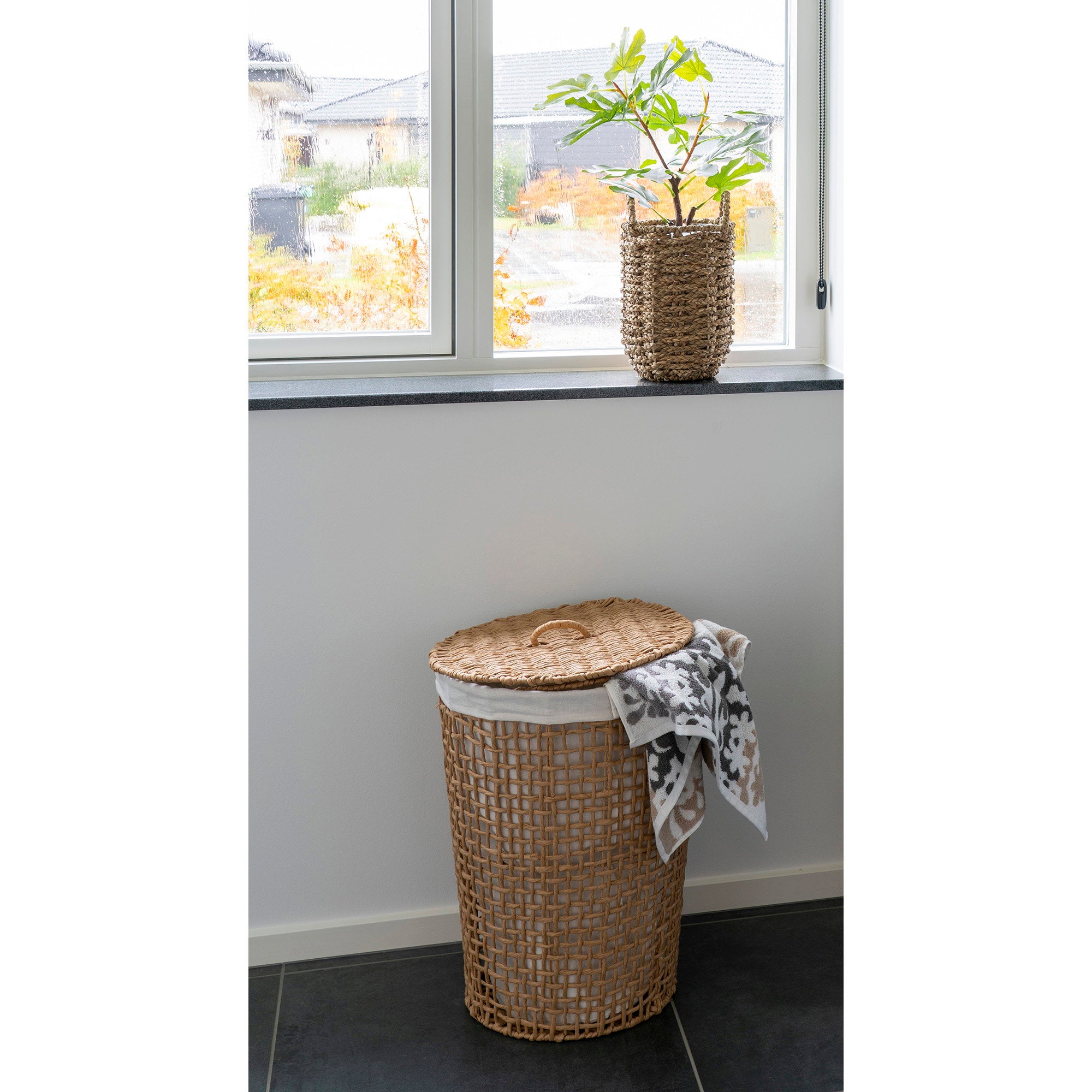 Panier à linge Pomal papier tressé en ambiance salle de bain lumineuse avec serviette et plante