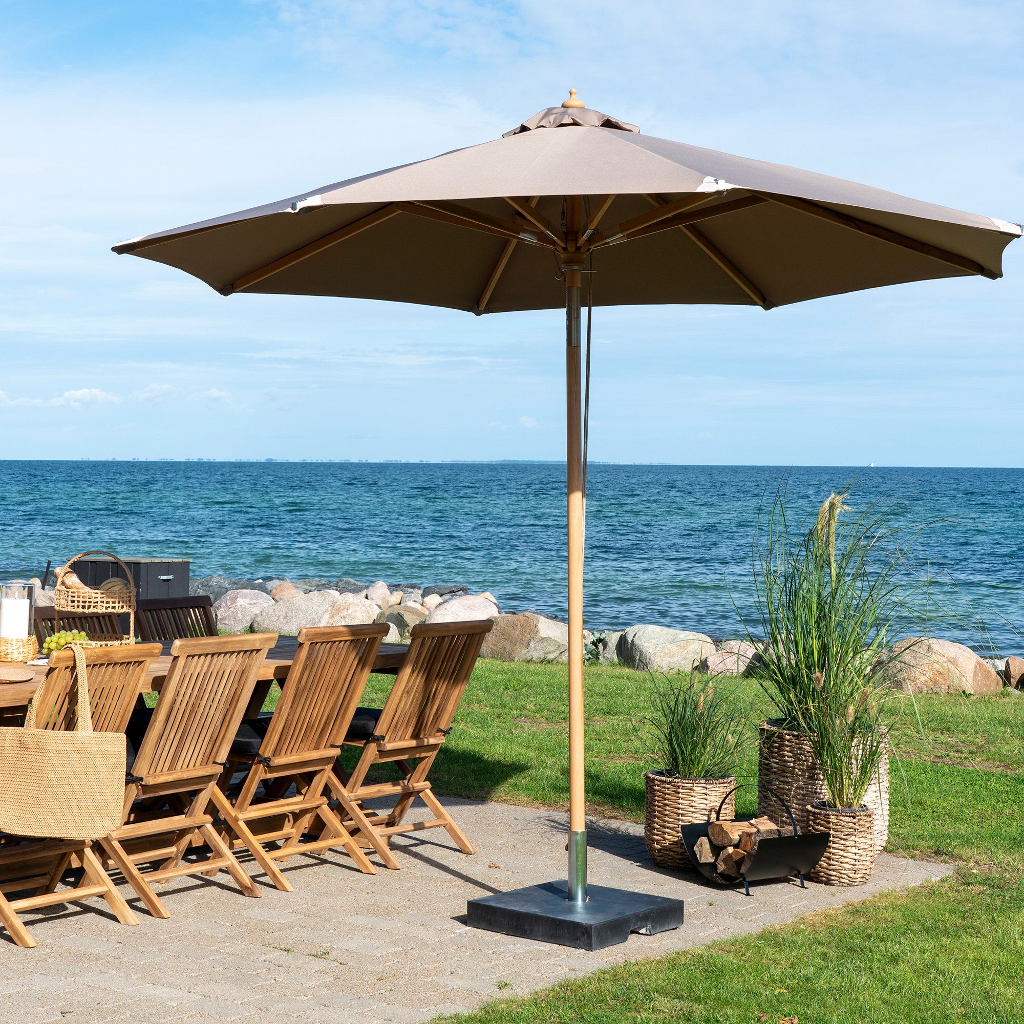 Parasol Austin taupe Ø300 cm sur terrasse bord de mer grande table teck ambiance estivale