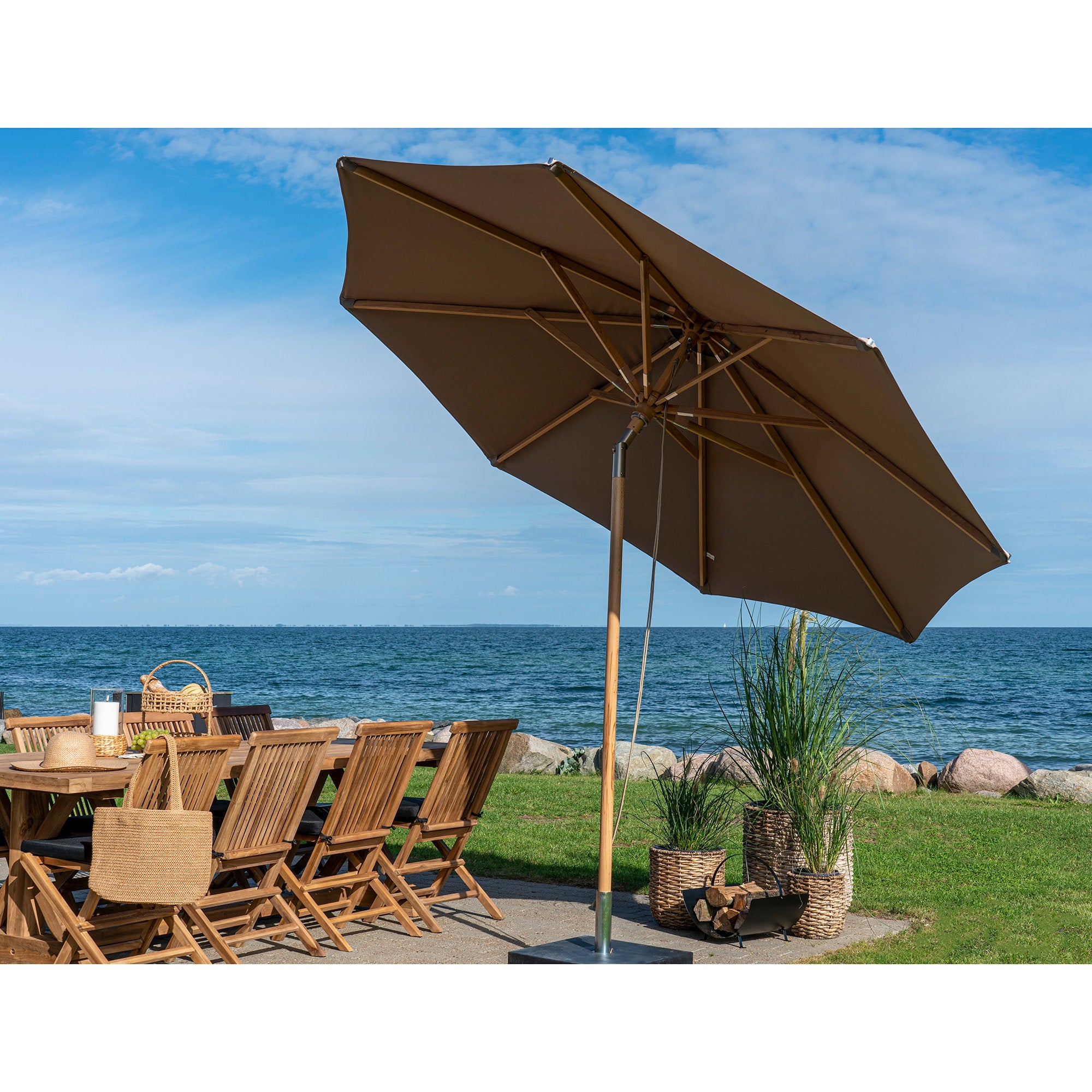 Parasol Austin taupe incliné sur terrasse bord de mer avec salon jardin teck