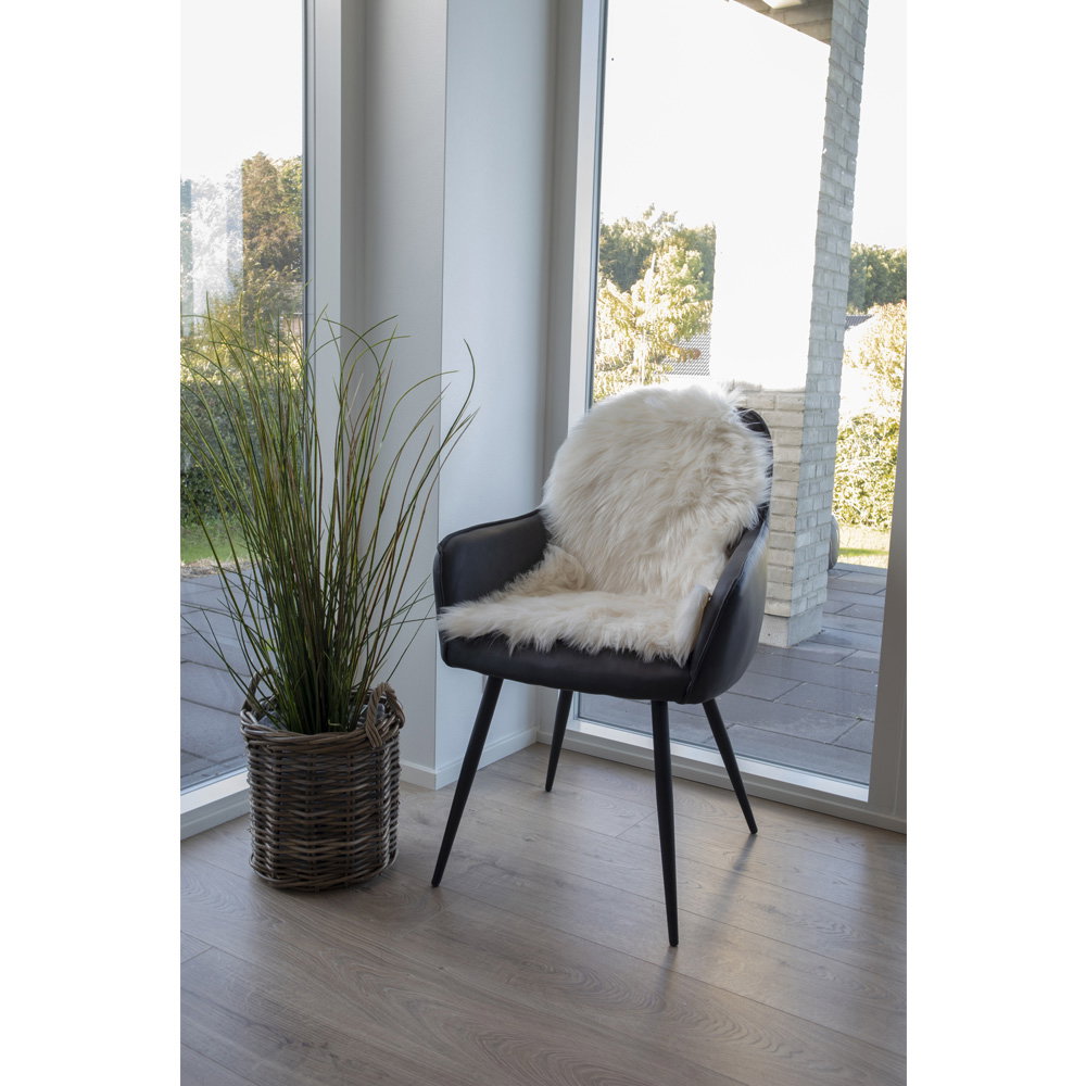 Fausse fourrure ivoire posée sur fauteuil noir cuir ambiance nordique lumière naturelle