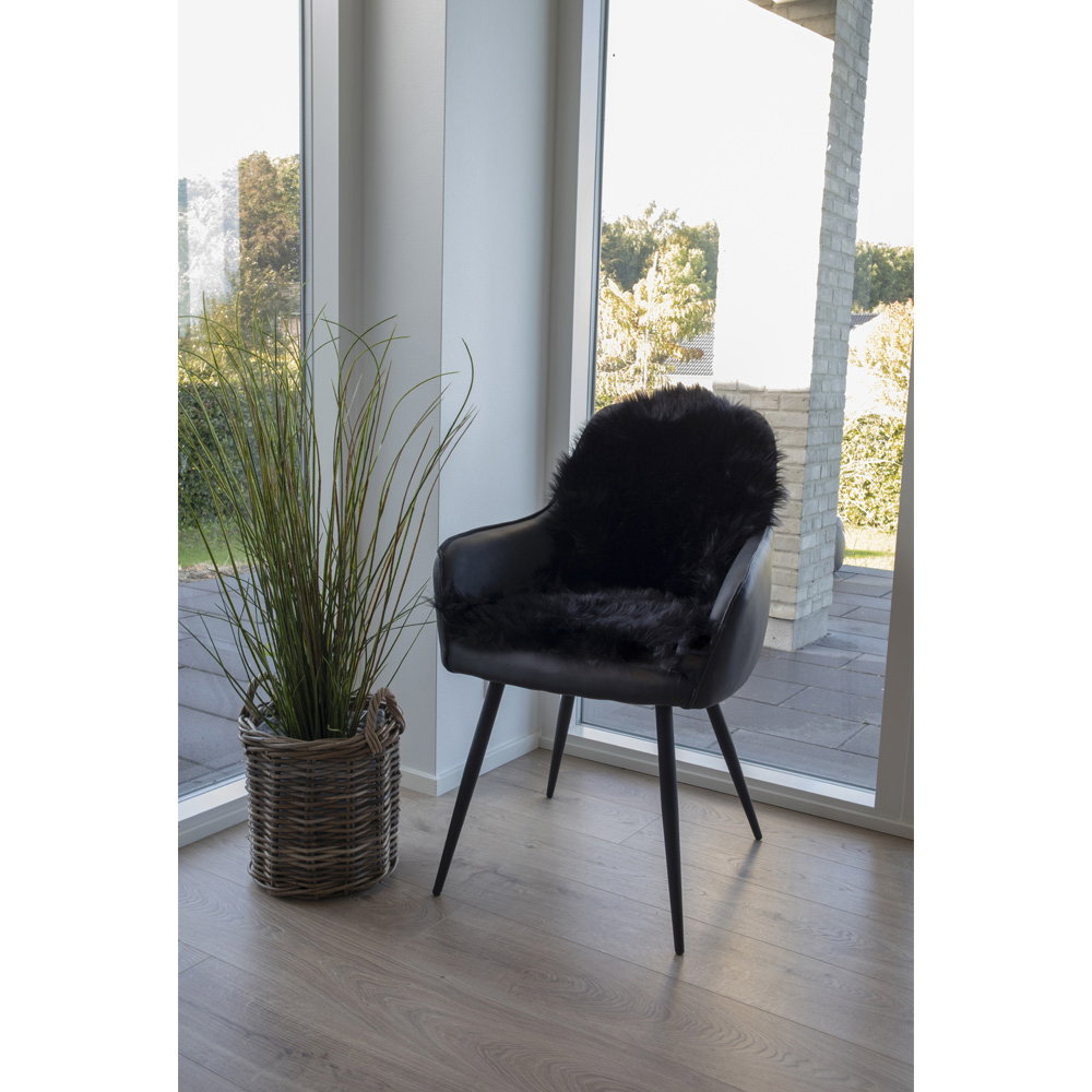 Fausse fourrure noire posée sur fauteuil noir cuir ambiance nordique lumineuse