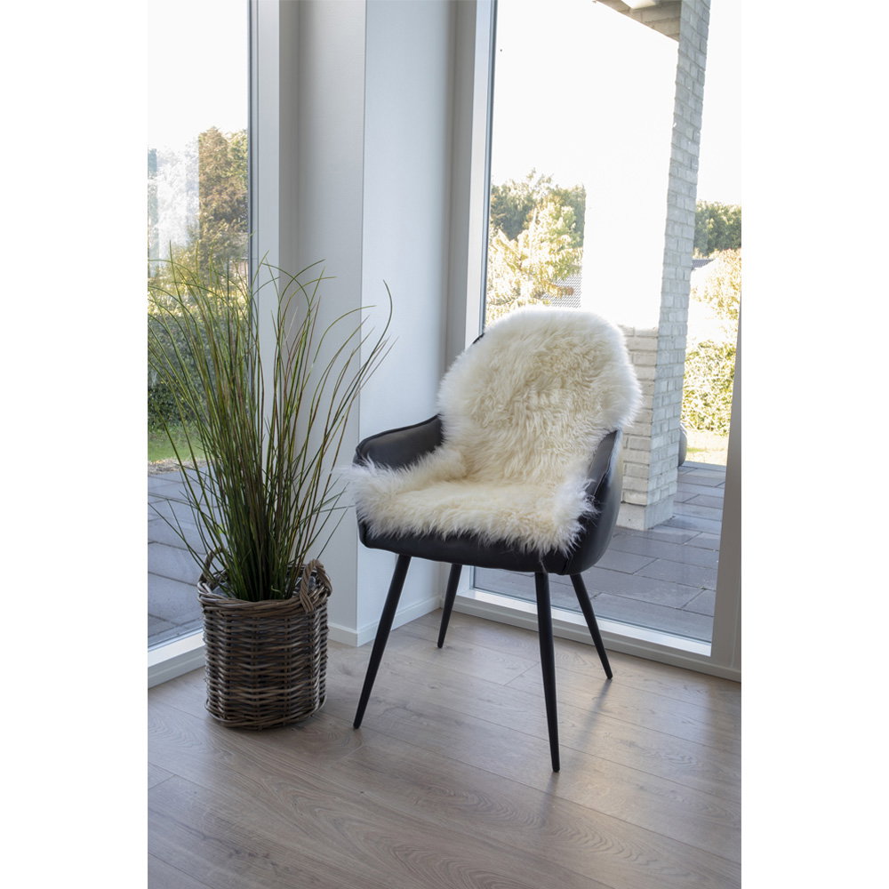 Vraie peau d'agneau ivoire posée sur fauteuil noir cuir ambiance scandinave lumière naturelle
