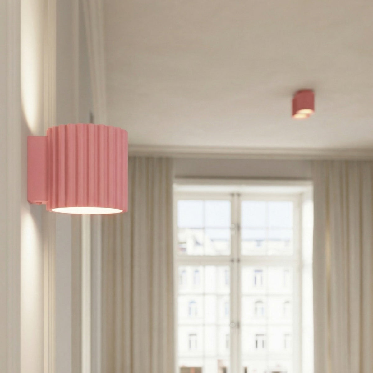 Applique murale Aura en laque rose au premier plan et plafonnier Aura à deux spots au plafond en arrière-plan