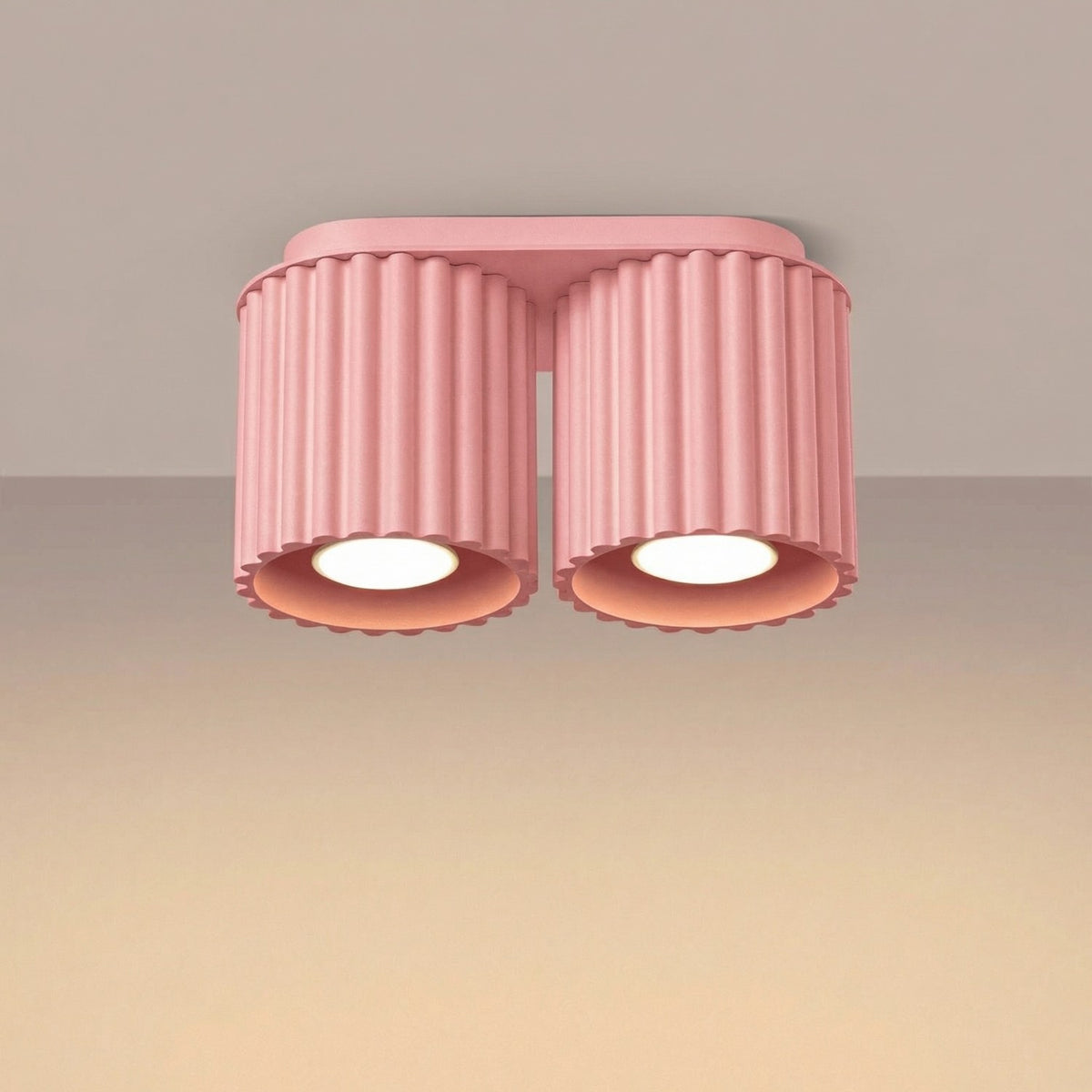 Plafonnier Aura en laque rose allumé au plafond sous une lumière chaude
