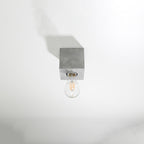 Plafonnier Ariz en béton brut, cube à ampoule apparente, vue de profil